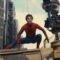 Tom Holland vestido como Homem-Aranha agachado sobre um veículo militar durante as filmagens de uma cena de ação, com um equipamento de câmera suspenso ao lado capturando a cena. Ao fundo, é possível ver prédios modernos e o céu parcialmente nublado.