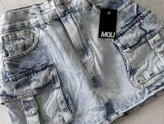 A imagem mostra um par de calças jeans da marca MOLI. As calças parecem estar desgastadas e com um efeito de lavagem ácida, criando um visual envelhecido e desbotado. Elas possuem bolsos e detalhes típicos de jeans, como costuras aparentes. O destaque é o tag da marca MOLI, que está visível na parte frontal das calças