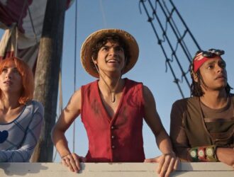 A direita três pessoas olham para o horizonte dentro de um barco