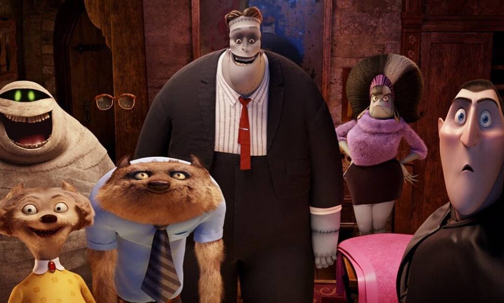 Cena do filme “Hotel Transilvânia” mostra um grupo de monstros reunidos, incluindo figuras como Drácula, Frankenstein, um lobisomem e uma múmia. Todos estão em um ambiente interno e parecem surpresos ou curiosos, criando um clima divertido e cômico típico da animação.