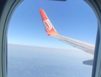 Imagem mostra janela do avião, céu azul e o símbolo da Gol