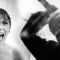 A imagem é uma cena icônica do filme “Psicose” (1960), dirigida por Alfred Hitchcock. Em preto e branco, mostra à esquerda uma mulher gritando em pânico dentro de um chuveiro, enquanto à direita aparece a silhueta de uma figura levantando uma faca, prestes a atacar. Essa sequência é uma das mais famosas da história do cinema de terror