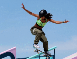 Imagem exibe uma jovem em uma manobra de skate