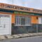 A imagem mostra a fachada de um prédio identificado como "Sindicato Nacional dos Aposentados", organização suspeita de envolvimento no esquema de desvio de pensões dos aposentadas no Brasil. A estrutura tem uma fachada nas cores laranja e branca, com calçada de ladrilhos em frente.