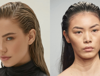 Duas mulheres posam com o cabelo no estilo wet hair, penteado com aparência molhada e polida. À esquerda, uma mulher com cabelo loiro puxado para trás com efeito molhado e pele clara usa uma blusa preta de gola alta, com maquiagem leve que destaca os olhos azuis e os lábios rosados. À direita, uma mulher com cabelo preto igualmente penteado para trás com efeito molhado exibe uma maquiagem minimalista, com foco na pele natural e sobrancelhas definidas. Ambas transmitem uma estética moderna e sofisticada